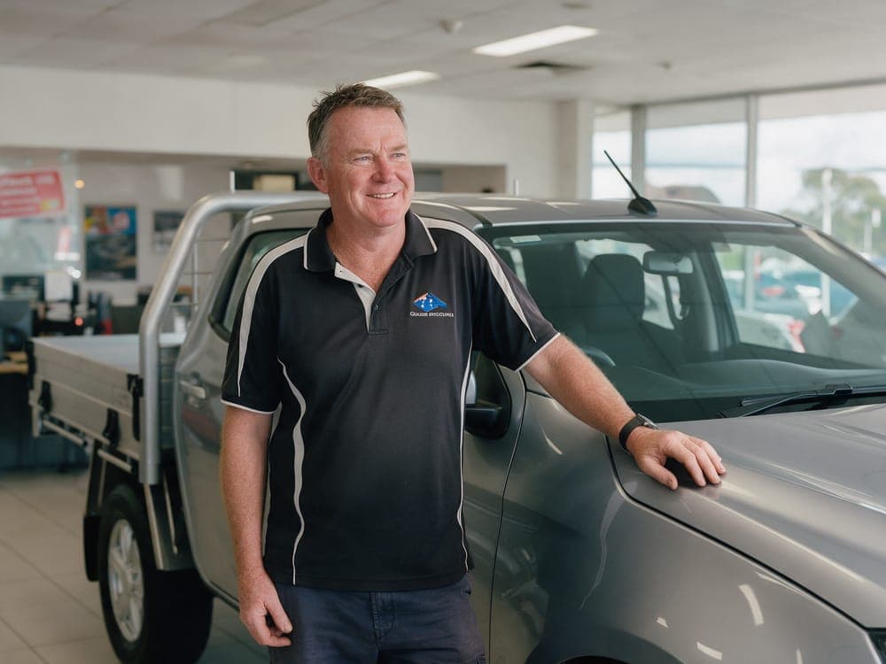 A dealership owner beside a new ute in his showroom
